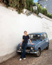 woman wearing mersea acton rib knit navy top leaning against small blue car
