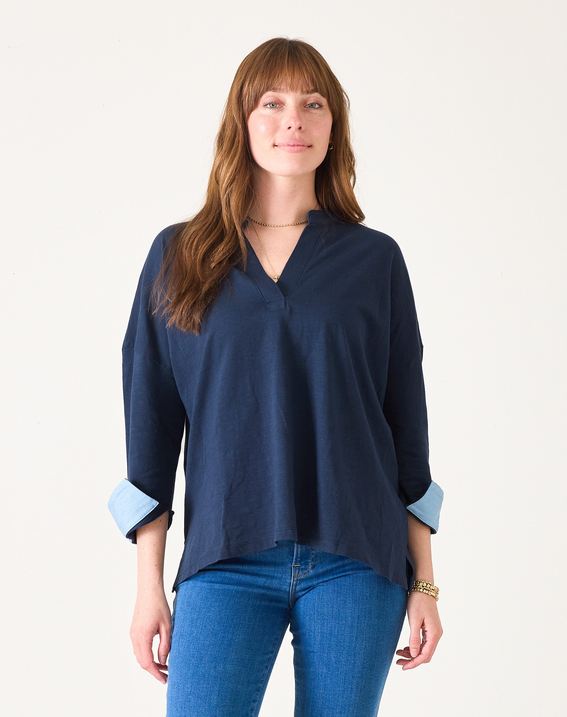 Woman wearing a navy blue blouse with rolled-up sleeves on a white background