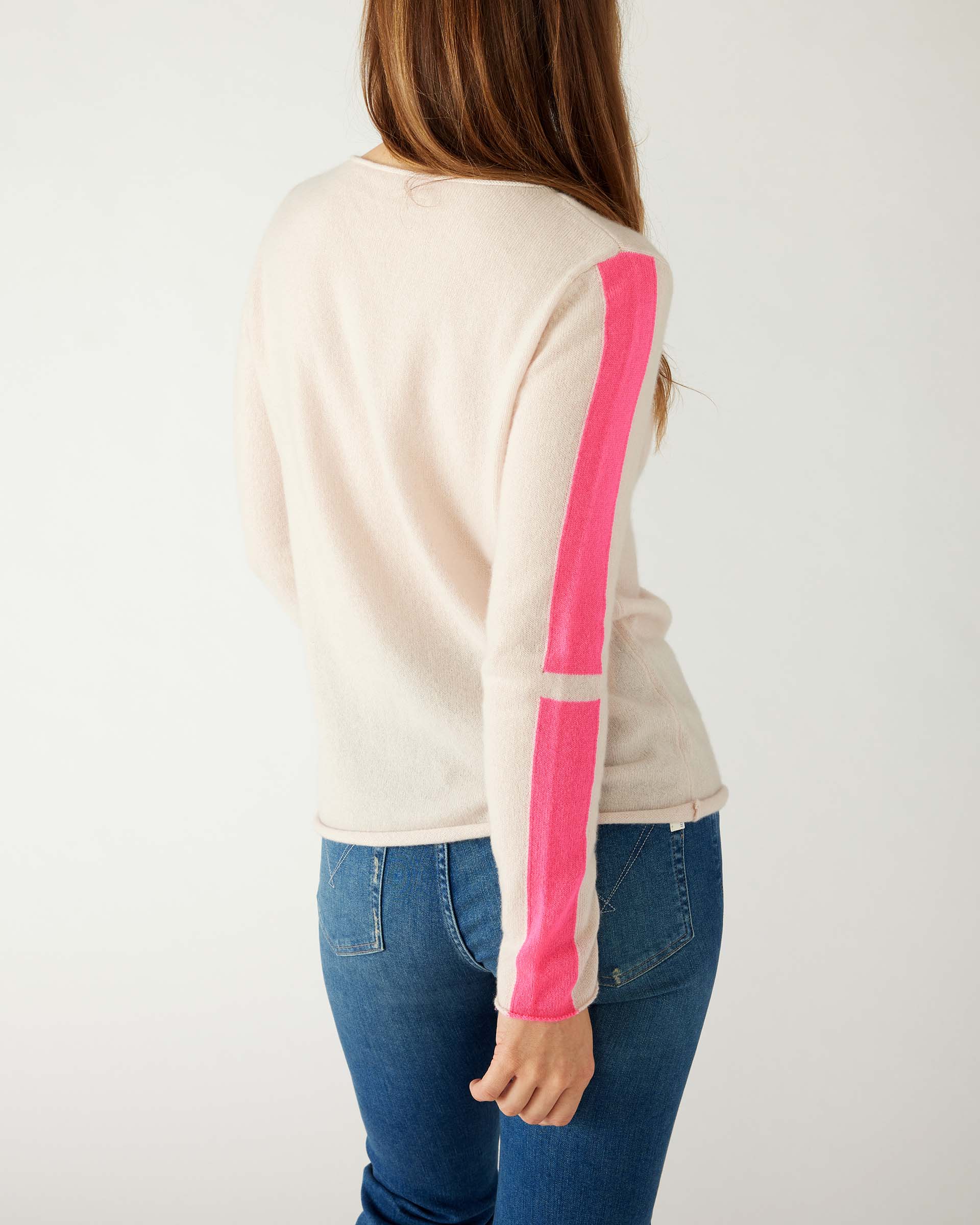 rear view of woman wearing mersea carmel cashmere sweater in champagne color with hot pink stripes down sleaves