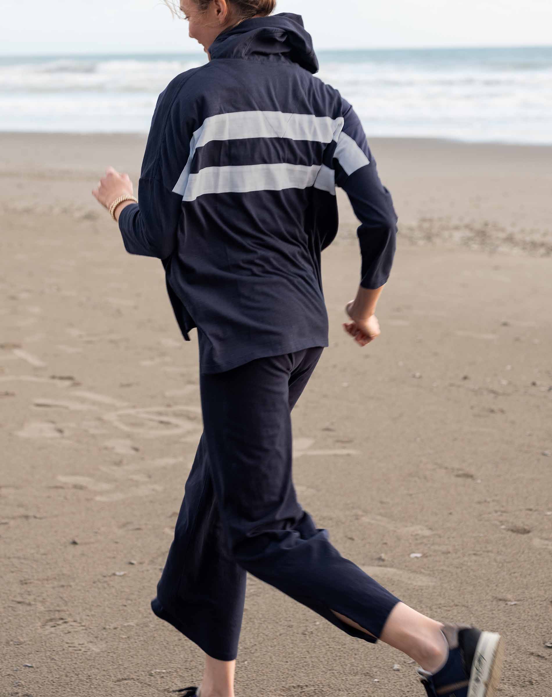 Person wearing a navy raincoat with white stripes on a beach