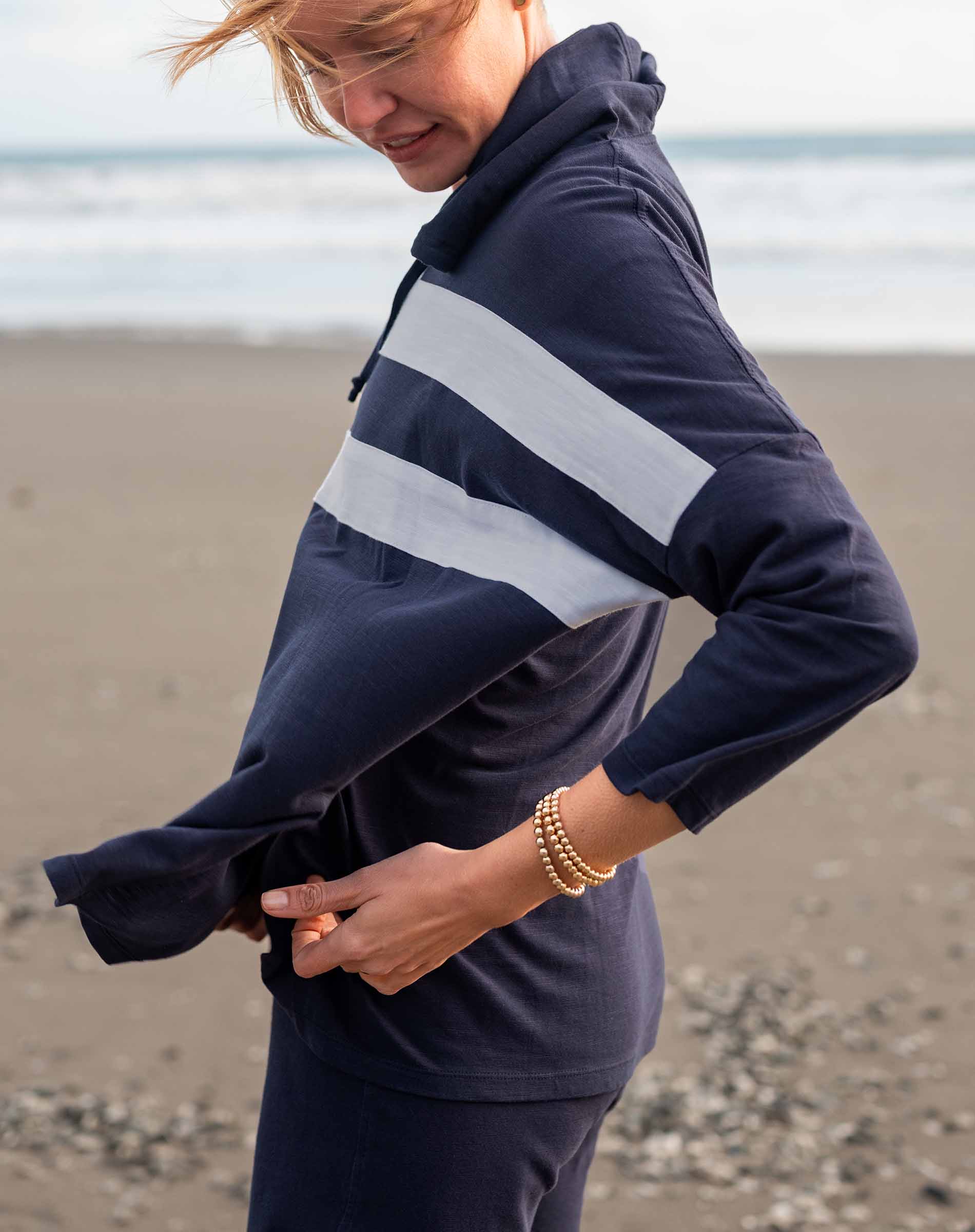 Person wearing a navy and white striped hoodie on a beach