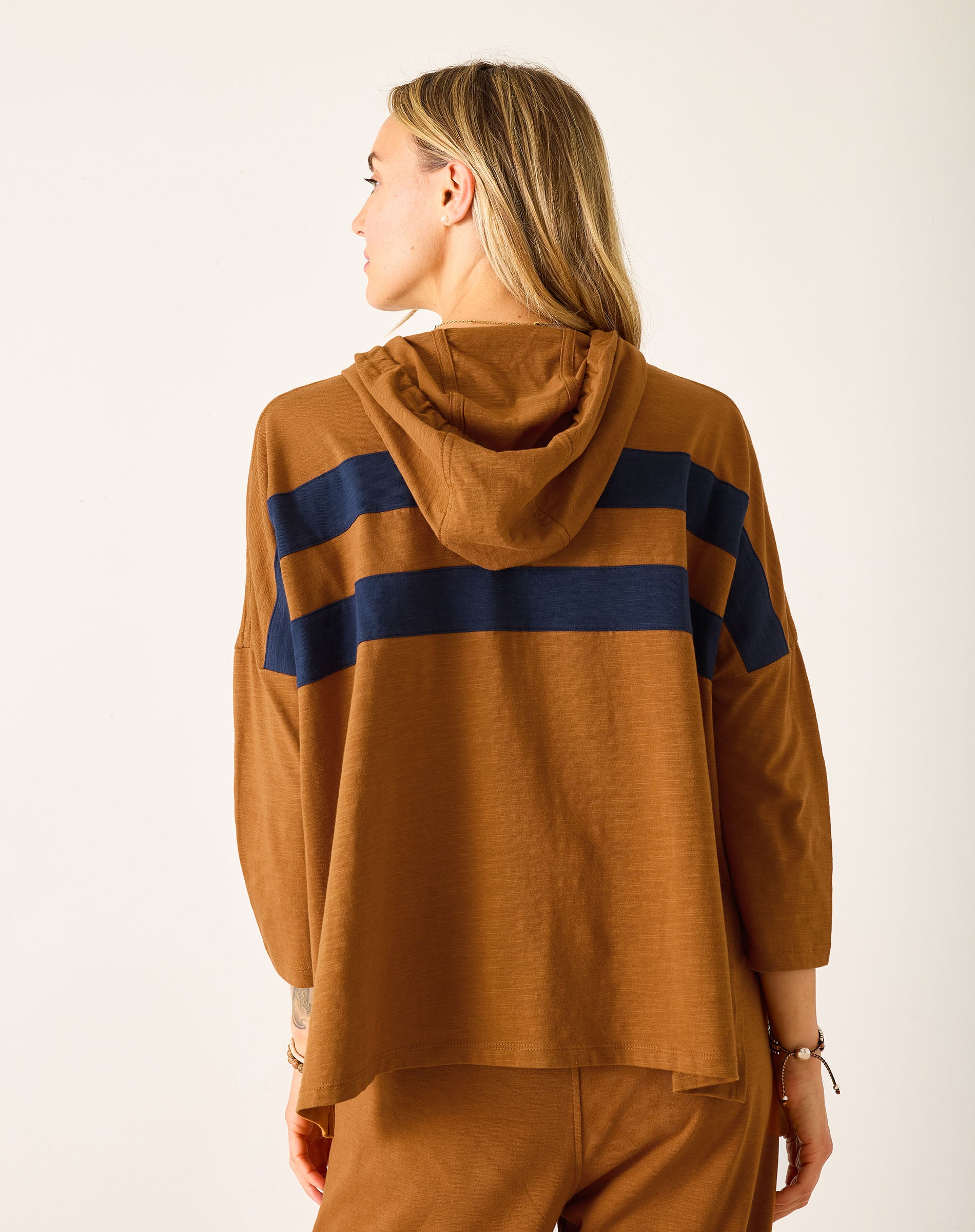 Person wearing a brown hoodie with blue stripes on a white background