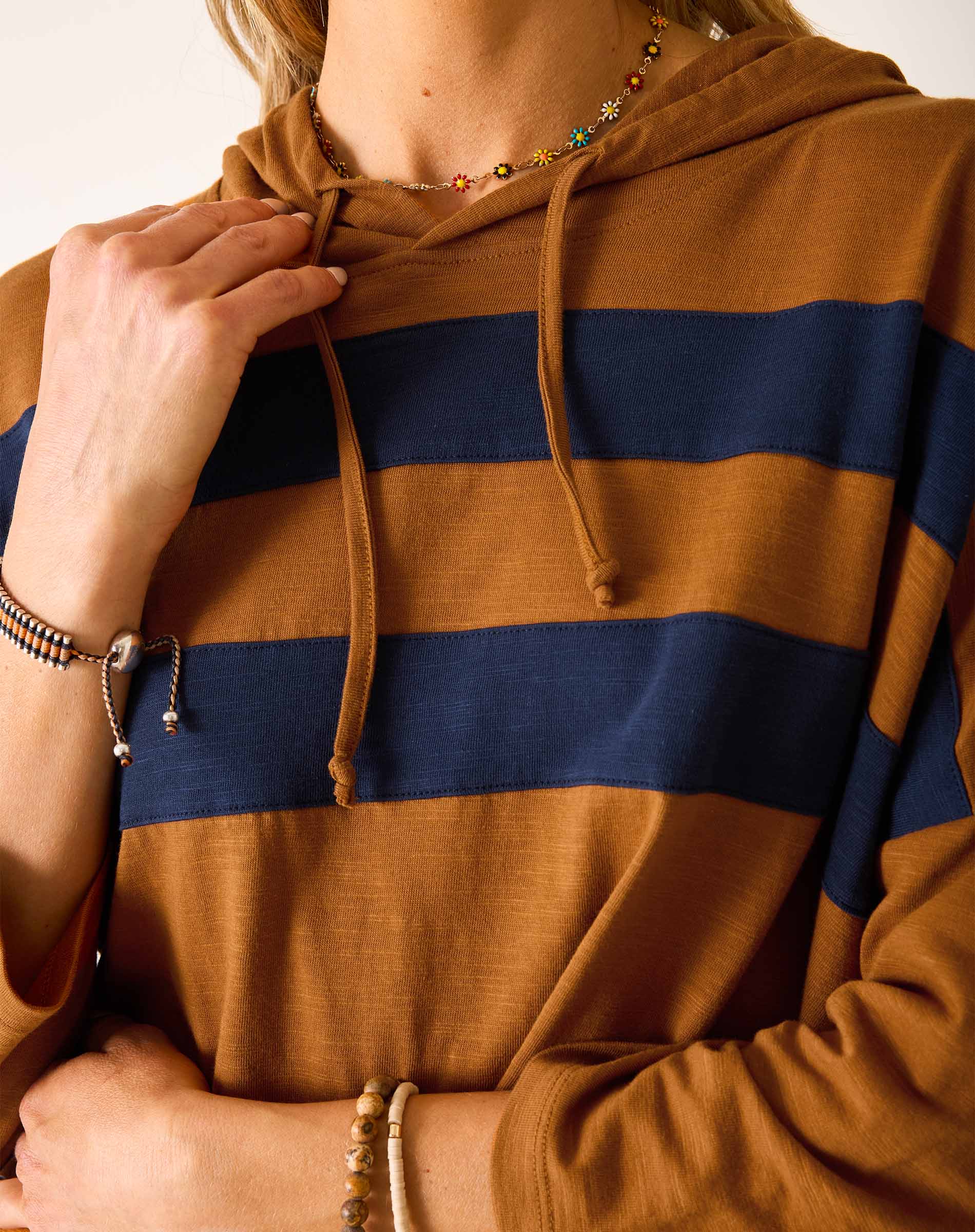 Close-up of a person wearing a brown and navy striped hoodie.