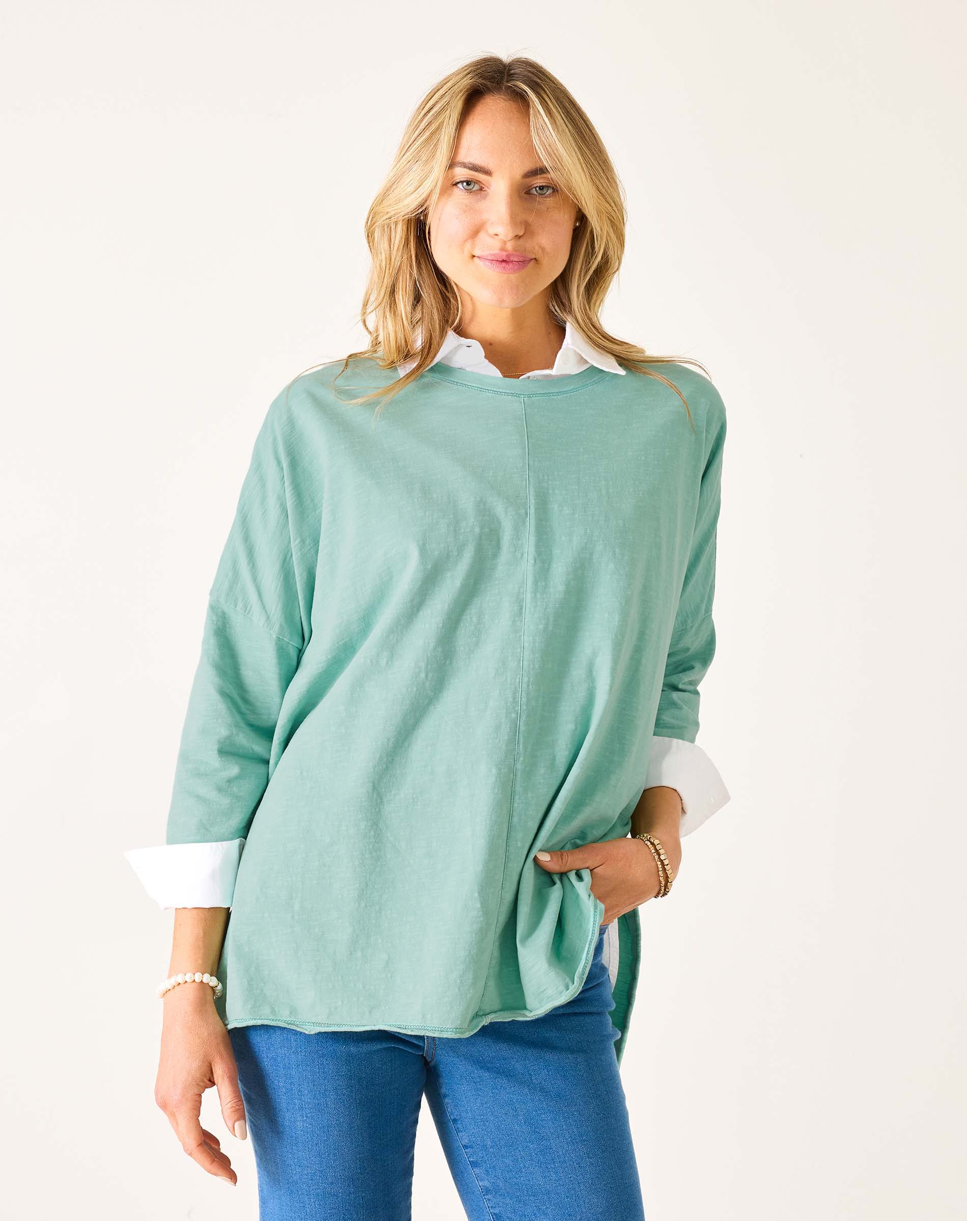 Woman wearing a light green sweater with white cuffs and collar on a white background