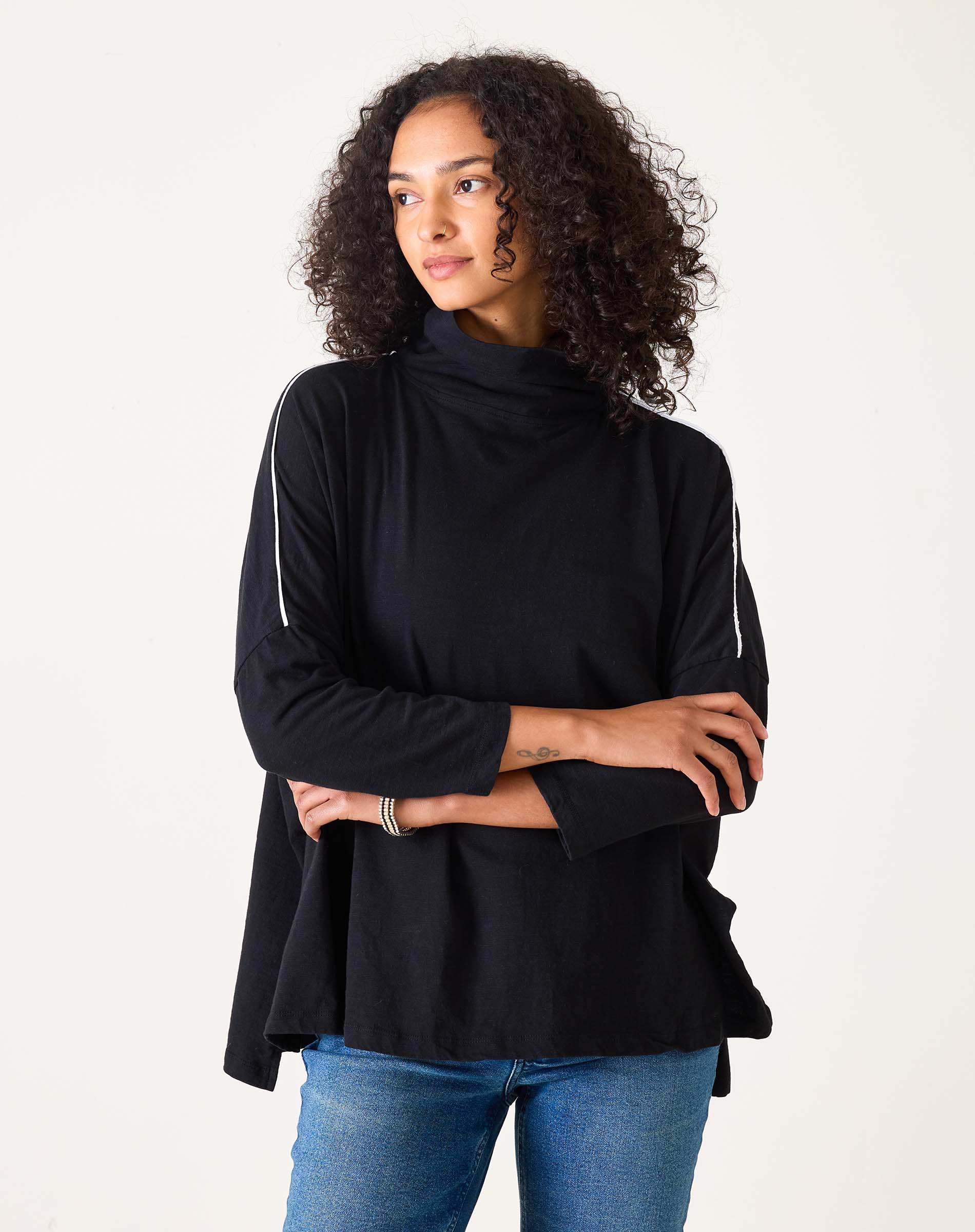 Woman wearing a black turtleneck sweater and blue jeans on a white background