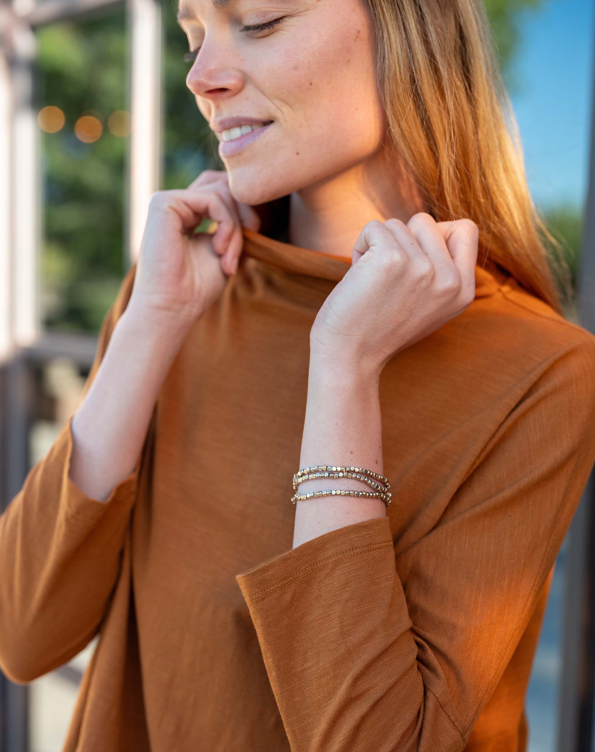 Woman wearing a brown shirt with a blurred outdoor background