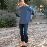 Woman wearing a blue long-sleeve top with a blurred natural background