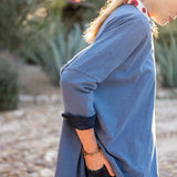 Woman wearing a blue long-sleeve top with a blurred natural background