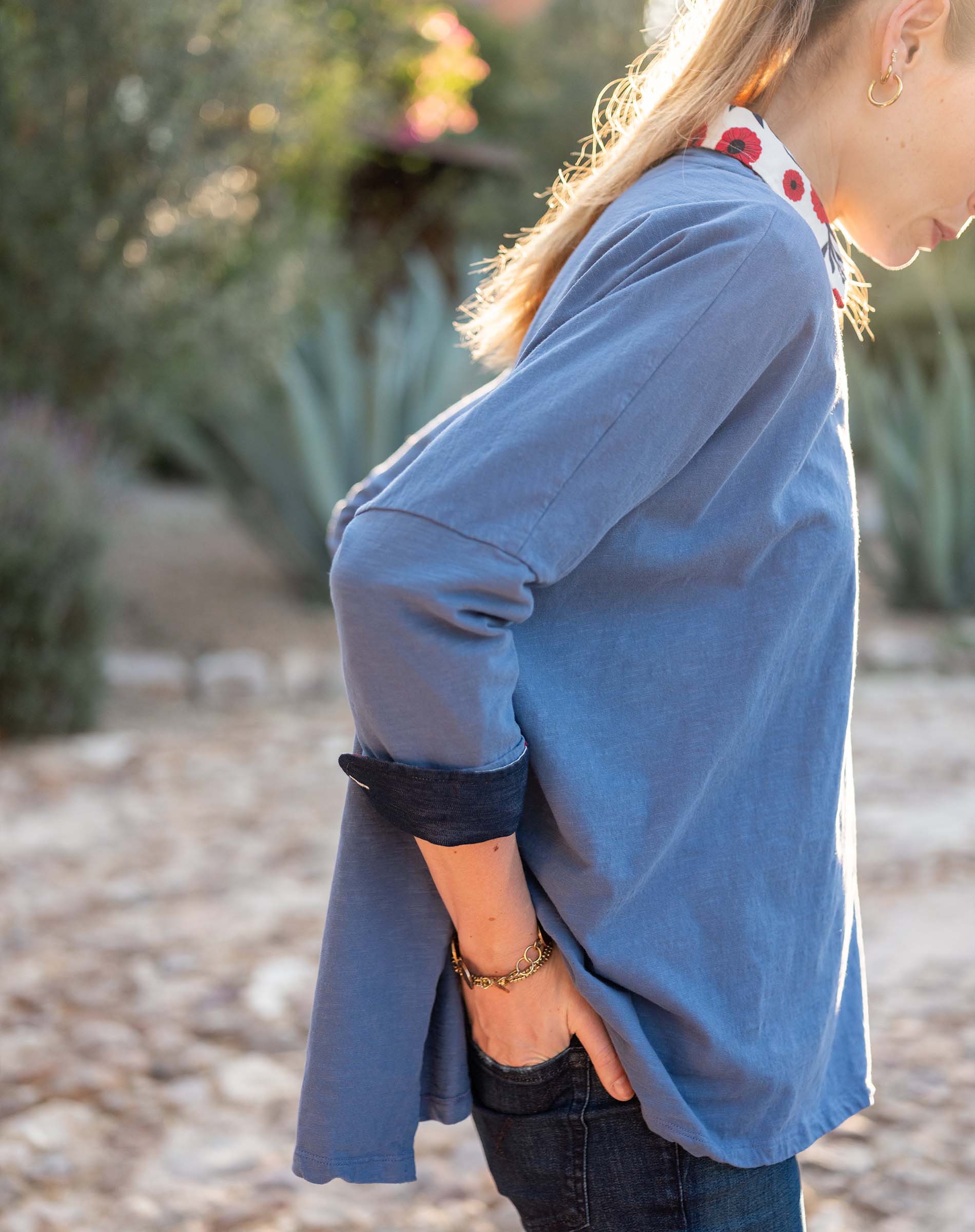 Woman wearing a blue long-sleeve top with a blurred natural background