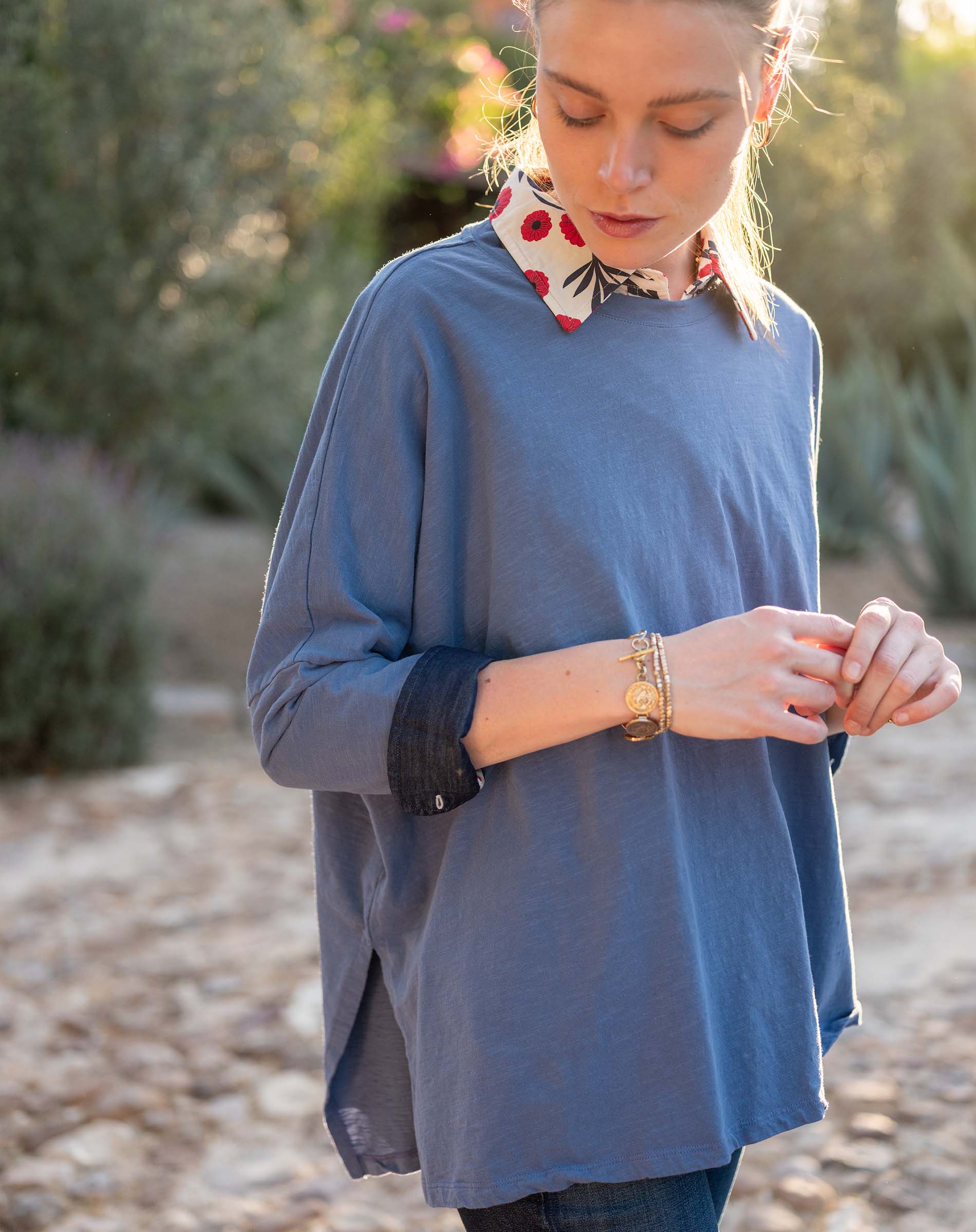 Woman wearing a blue long-sleeve top with a blurred natural background