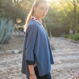 Woman wearing a blue long-sleeve top with a blurred natural background