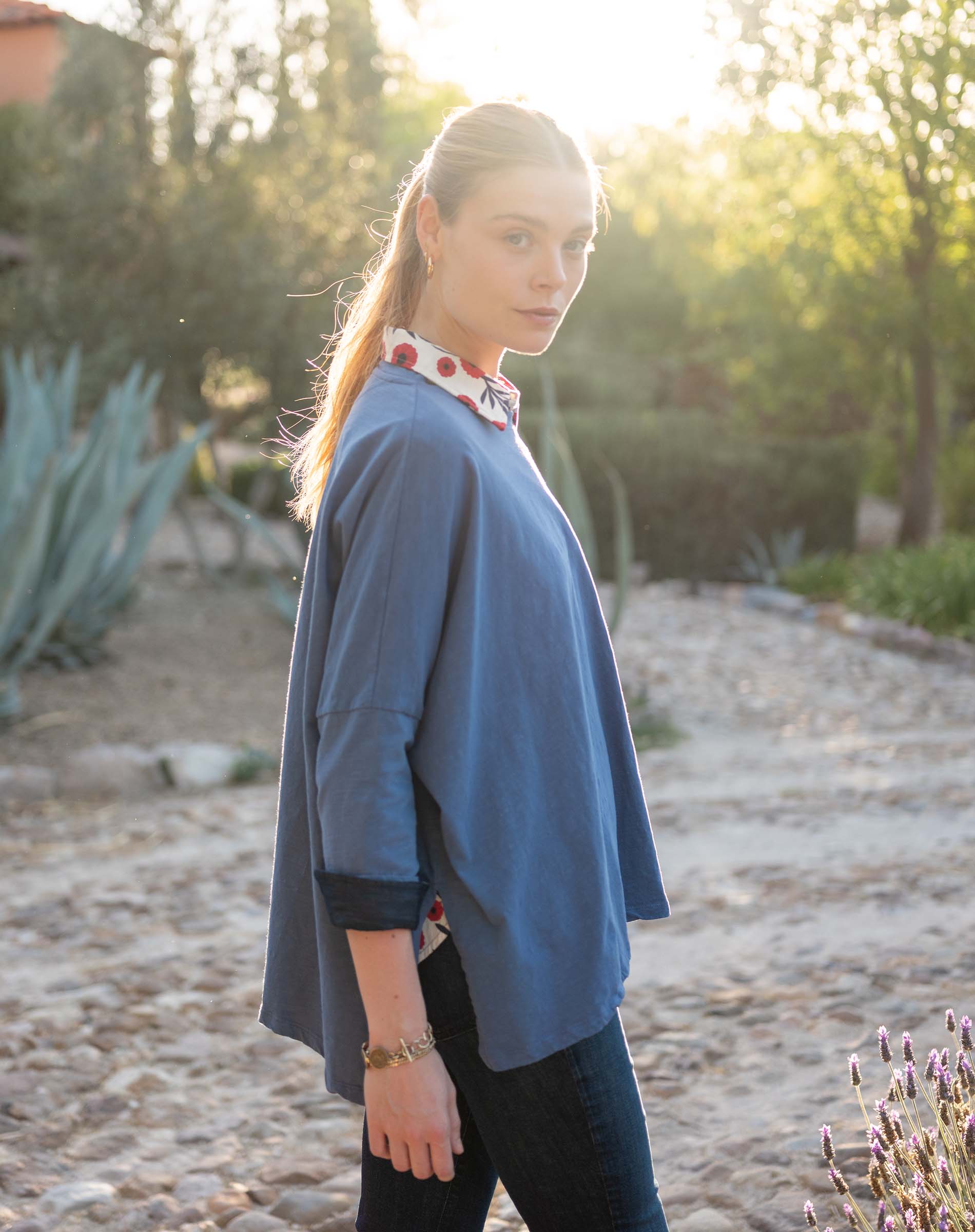 Woman wearing a blue long-sleeve top with a blurred natural background