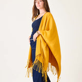 Woman wearing a yellow shawl over a navy outfit on a white background