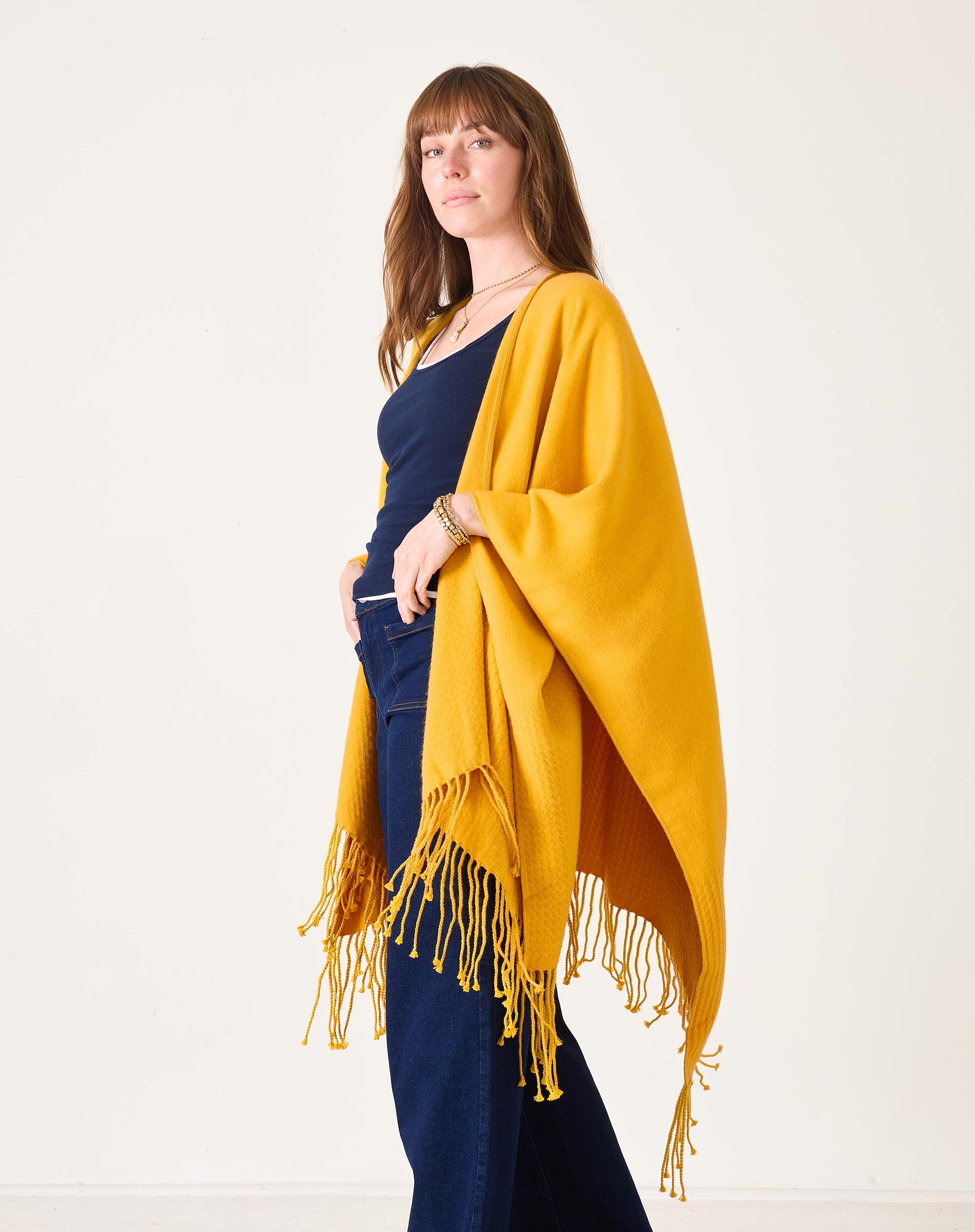 Woman wearing a yellow shawl over a navy outfit on a white background