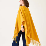 Woman wearing a yellow poncho with fringe on a white background