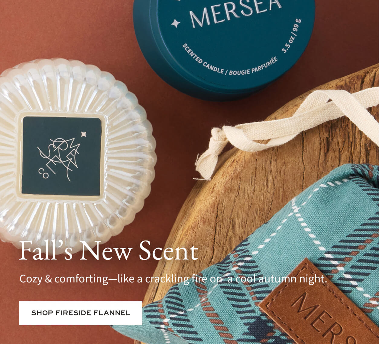 Mersea scented candle and decorative items on a brown background with text about 'Fall's New Scent'.