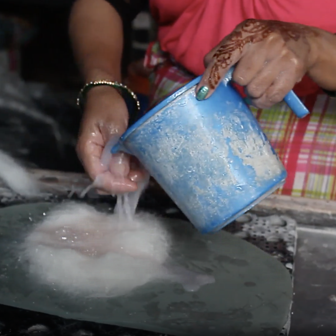 female pouring water on to felt fabric to create a felt coaster