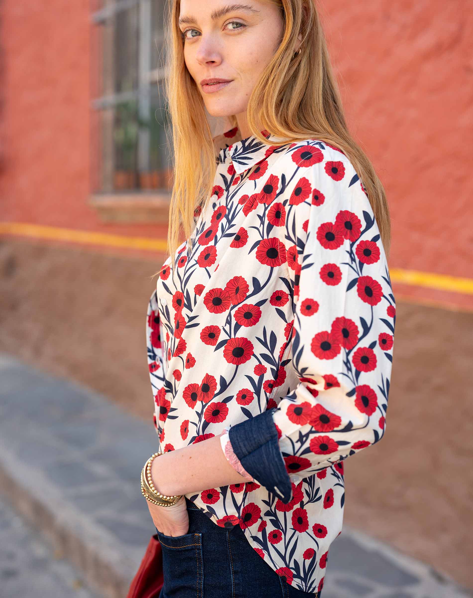 Woman wearing a floral blouse with red and black flowers against a blurred background