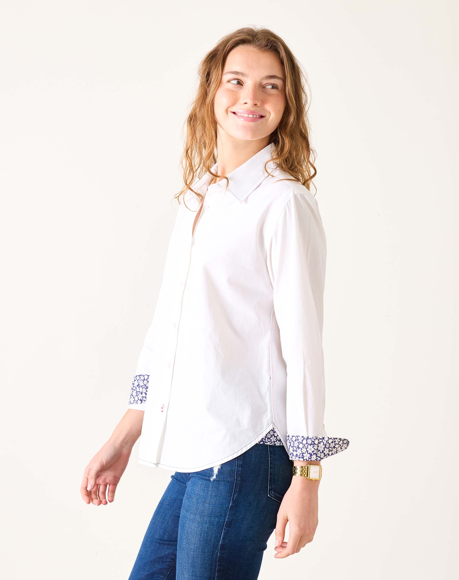 Woman wearing a white shirt with patterned cuffs on a plain background