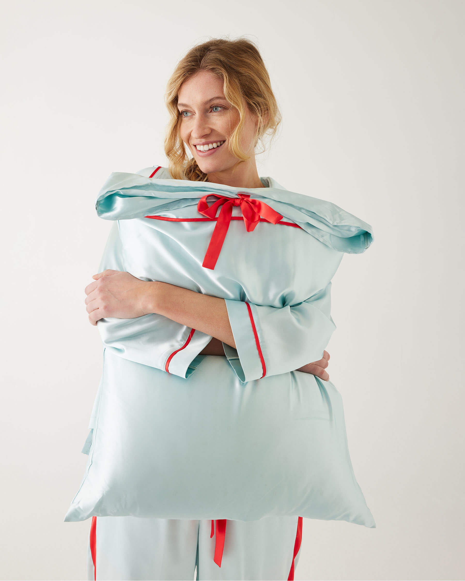 female holding Mersea aquamarine satin sailor pillowcase against white background