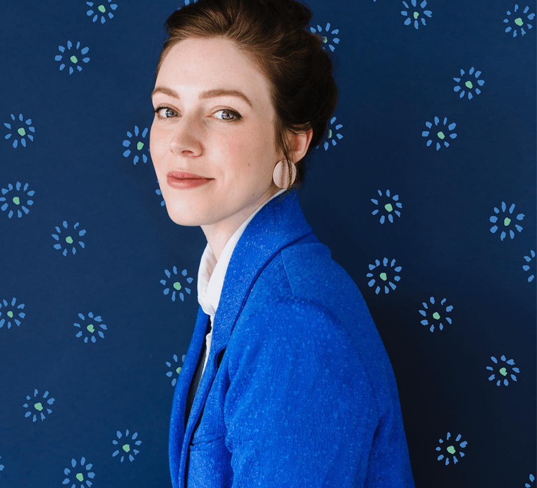 Artist Emily Taylor wearing a blue blazer in front of blue background