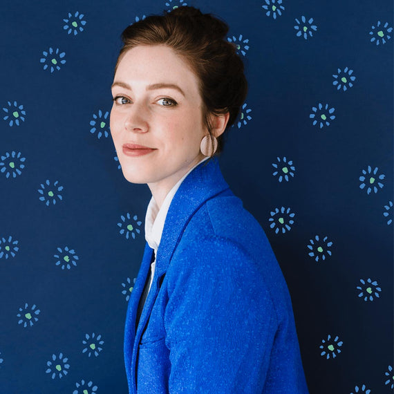 Artist Emily Taylor wearing a blue blazer in front of blue background