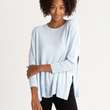 female wearing sky blue sweater with navy hearts and side slits on white background