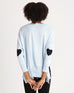 female backwards wearing sky blue sweater with navy hearts on each elbow on white background