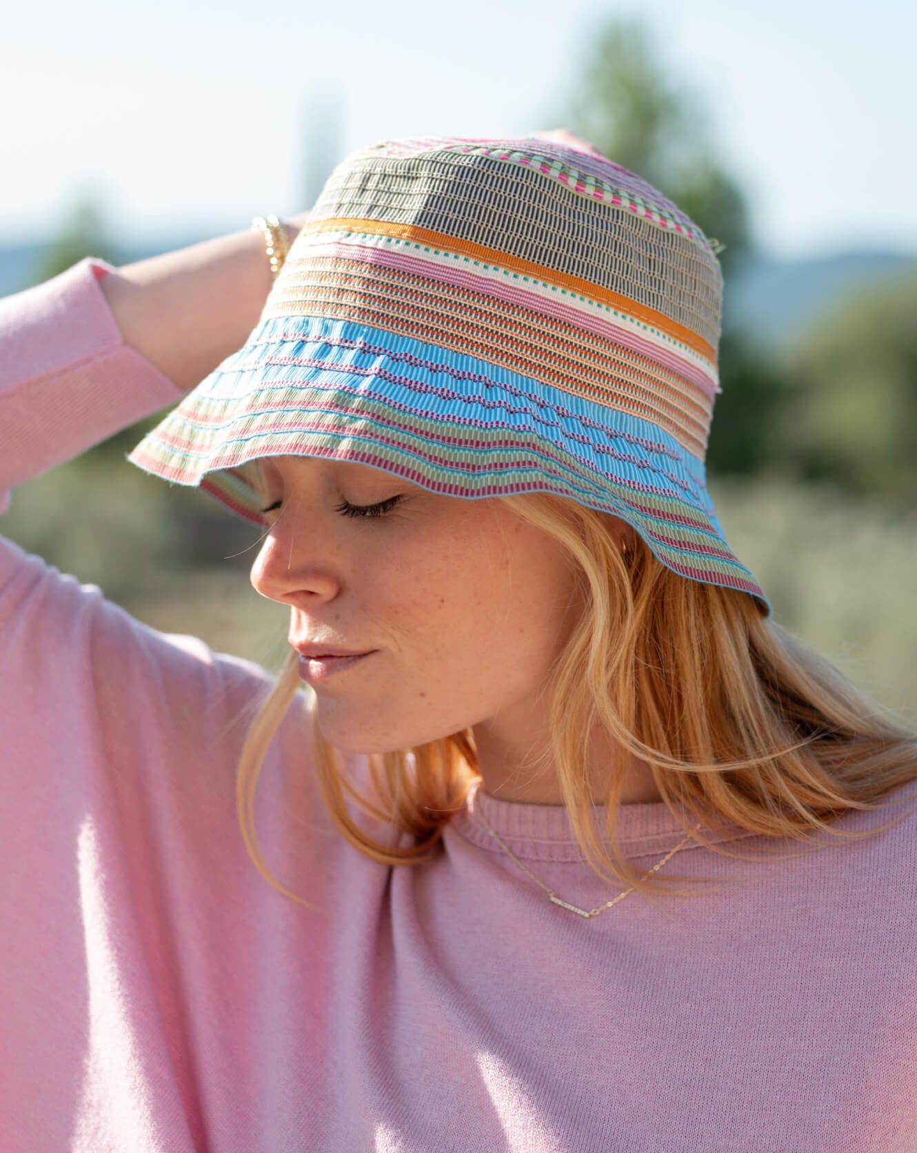 Woman wearing a colorful striped sun hat with a blurred natural background