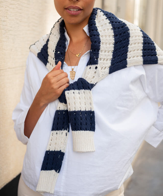 Image of a woman wearing a navy and white striped crocheted sweater over a white top