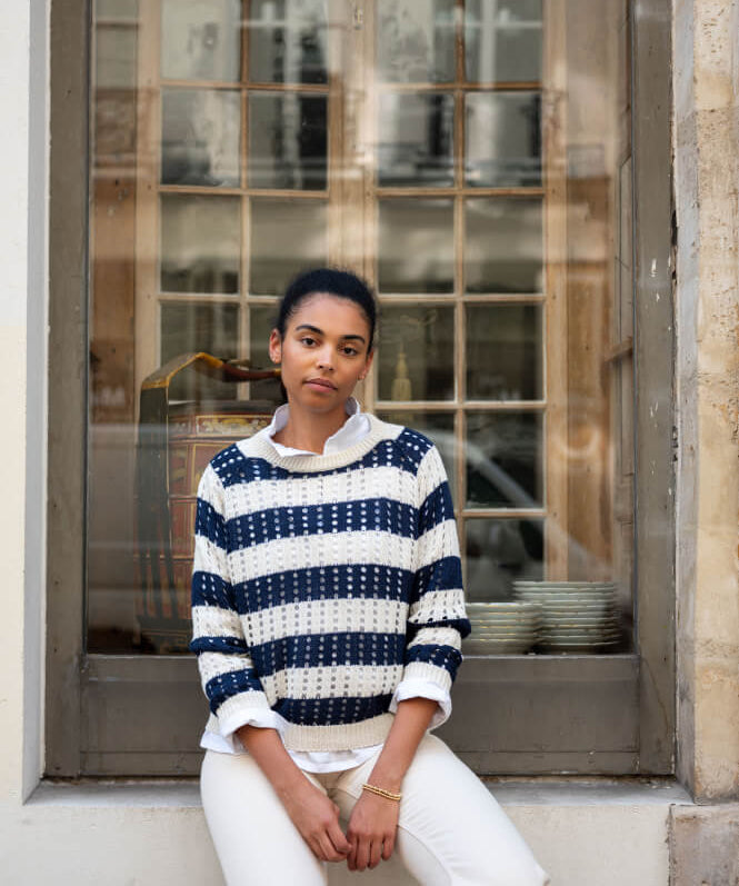 Image of a woman wearing a navy and white striped crocheted sweater