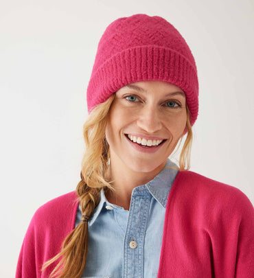 female wearing fuzzy pink beanie with chambray shirt and pink wrap on a white background