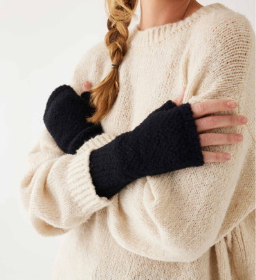 female wearing black fuzzy fingerless gloves and white sweater on a white background