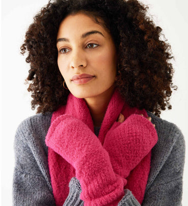 female wearing pink fuzzy fingerless gloves w/ matching scarf and grey sweater on white background