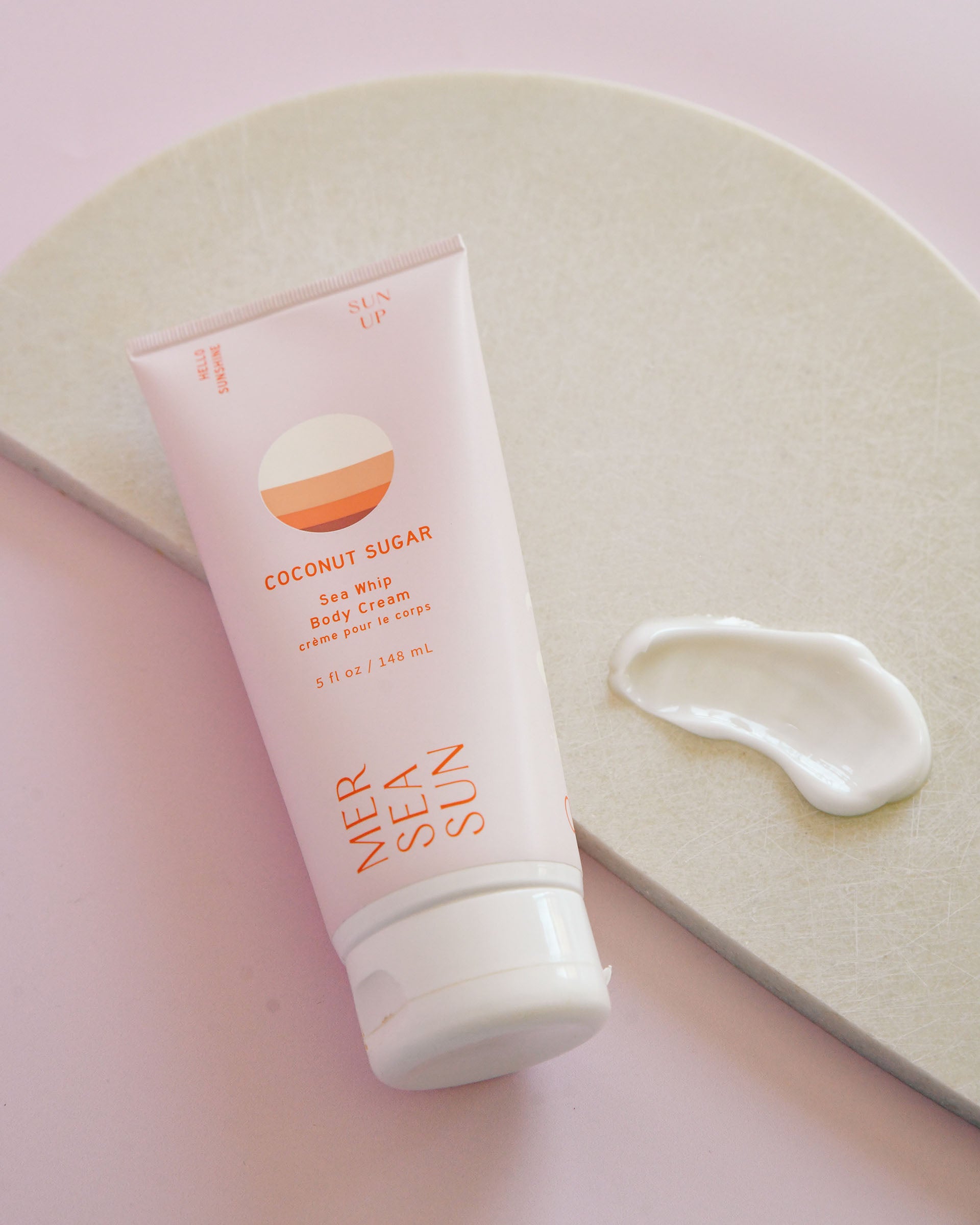 Coconut Sugar Sea Whip Body Cream MERSEA Sun. Pink and orange tube in front of pink background.
