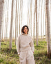 Women wearing a sea salt Mersea Beachside Turtleneck sweater standing in forest