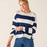 Woman wearing a blue and white striped sweater with blue jeans on a plain background