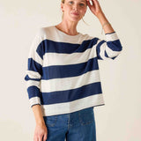 Woman wearing a blue and white striped sweater with blue jeans against a plain background