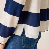 Navy and white striped sweater with blue jeans on a neutral background