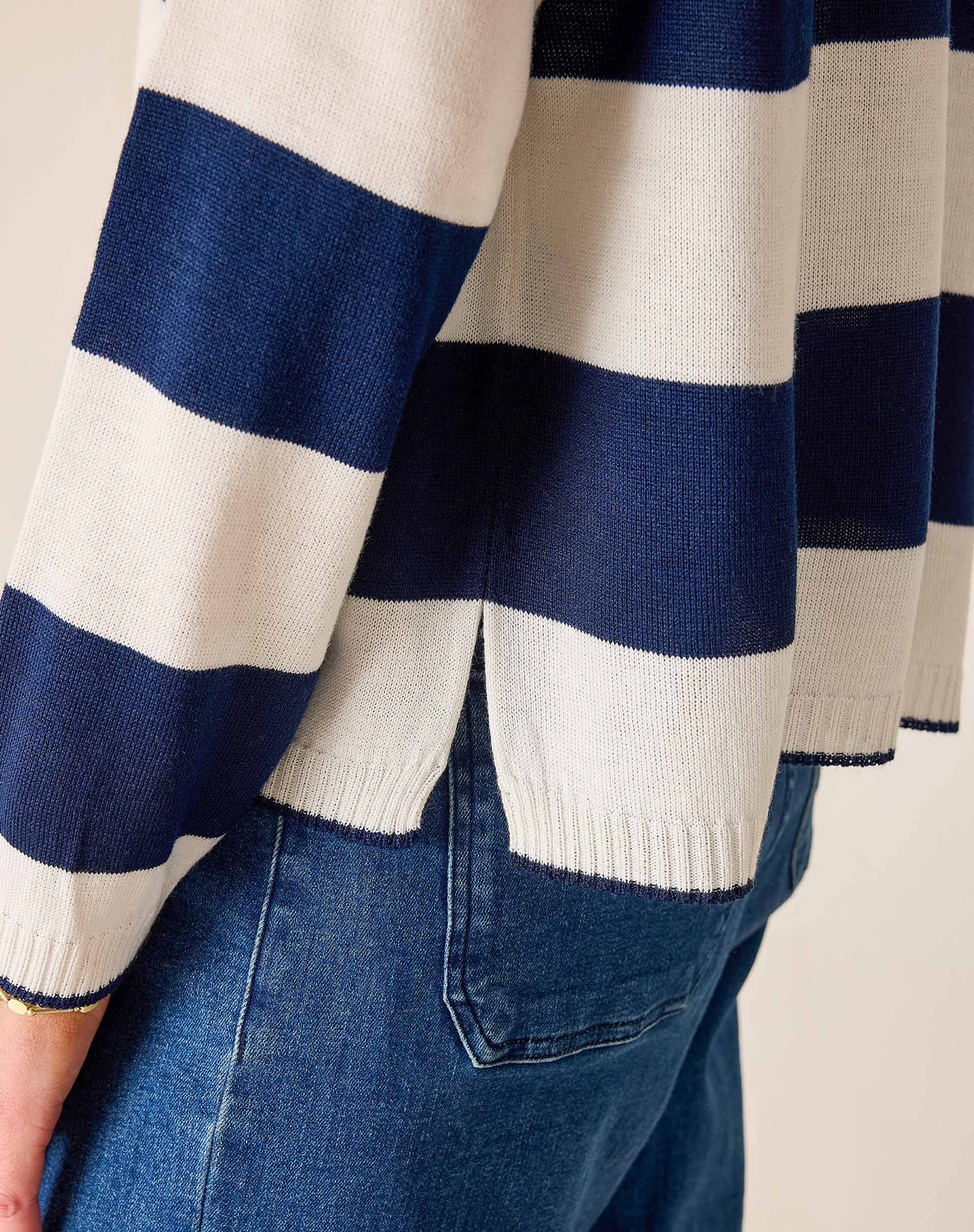 Navy and white striped sweater with blue jeans on a neutral background
