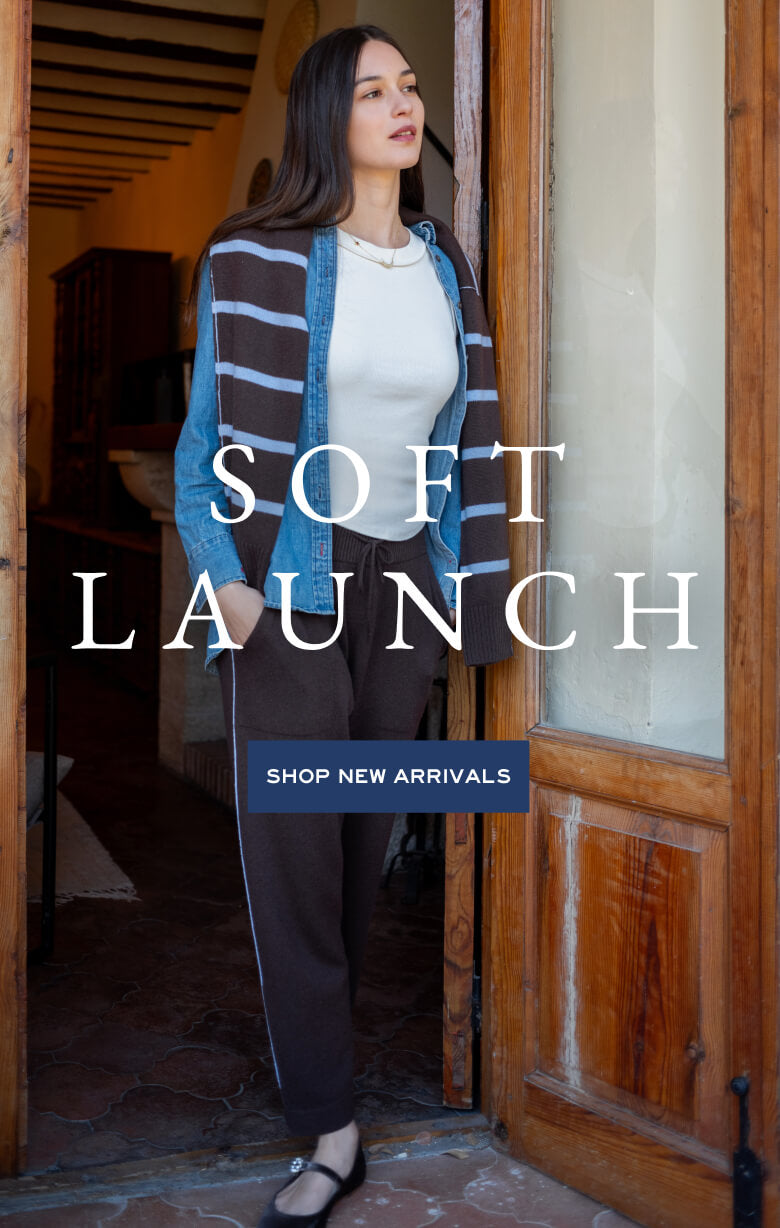 Soft Launch promotional banner featuring a woman in a blue and white striped cardigan and matching lounge pants standing in a doorway. Text: 'SOFT LAUNCH. SHOP NEW ARRIVALS'