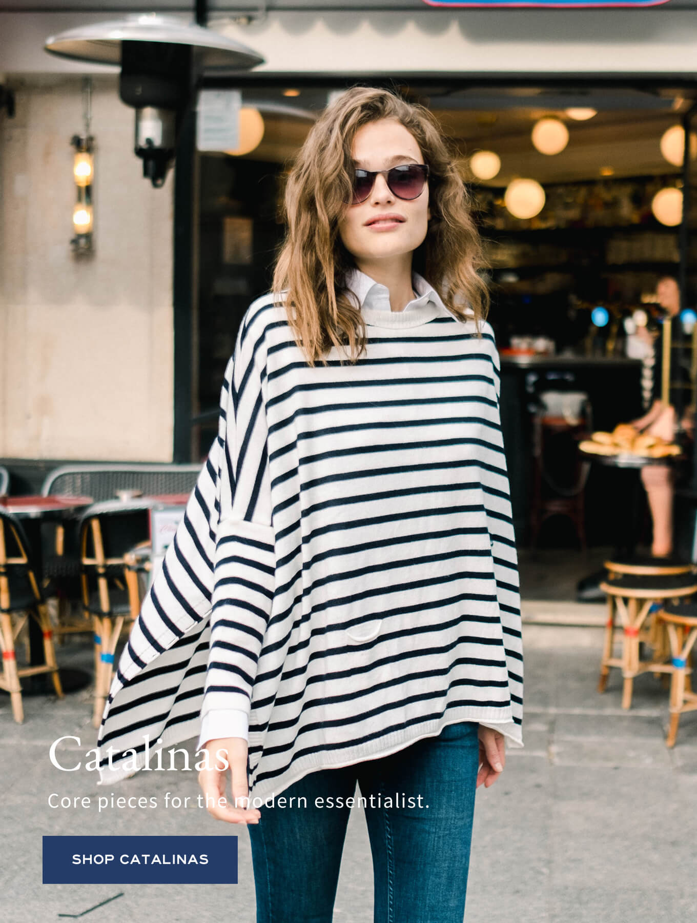 Navy and white striped knit poncho wrap over a white button-down shirt with blue jeans. Text: Catalina Core pieces for the modern essentialist. SHOP CATALINAS