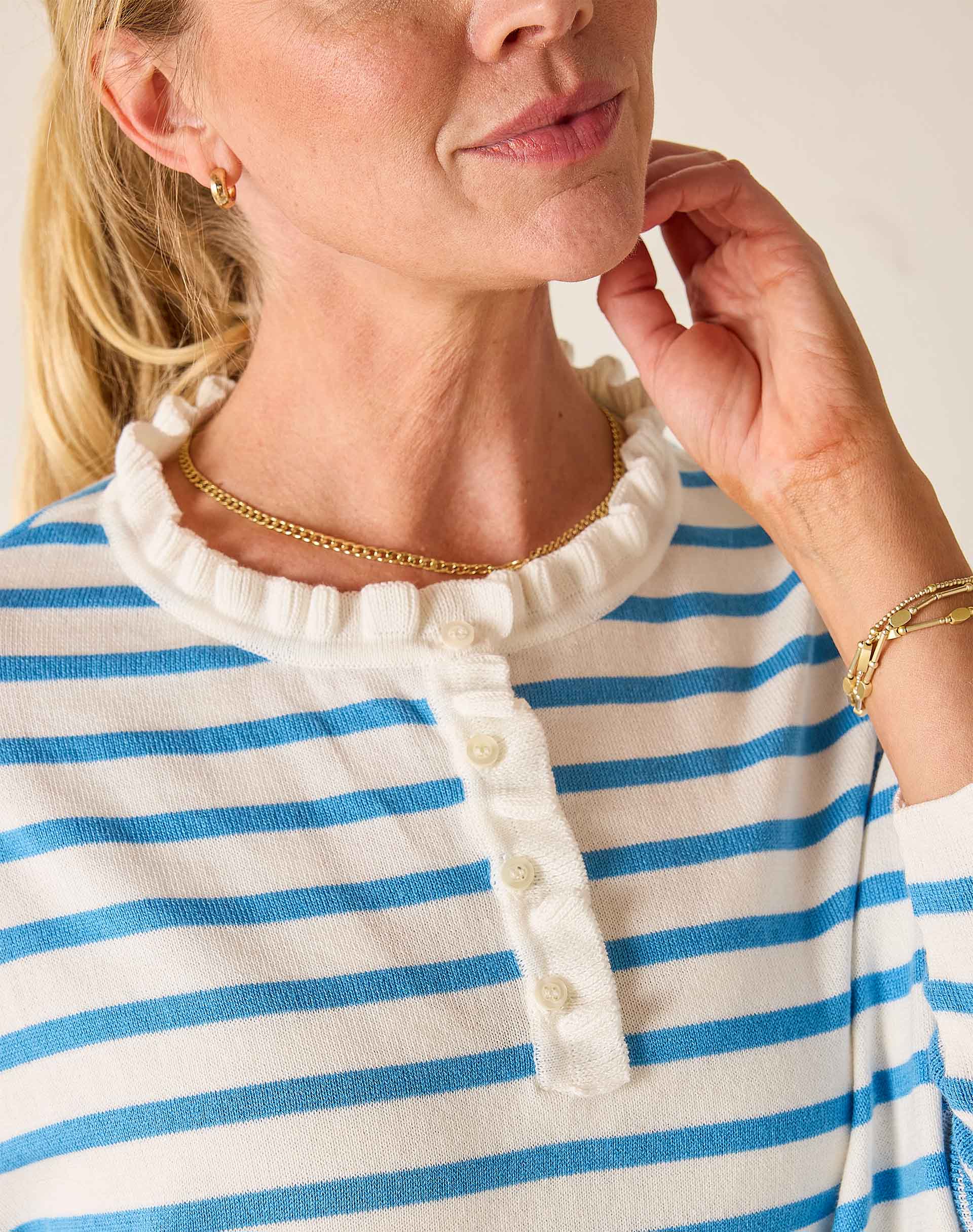 Woman wearing a blue and white striped shirt with a close-up of her neck and hand.