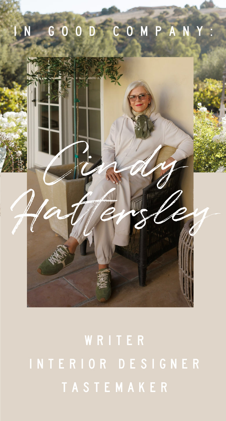 Promotional banner featuring a woman in casual beachwear sitting on a chair outdoors. Text: 'IN GOOD COMPANY. Cindy Hattersley WRITER INTERIOR DESIGNER TASTEMAKER'
