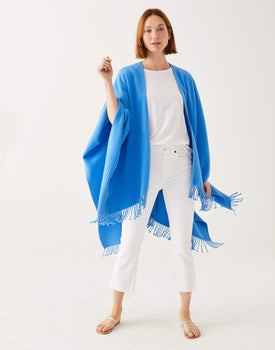Female wearing a blue classic wrap with white shirt and jeans in front of white wall