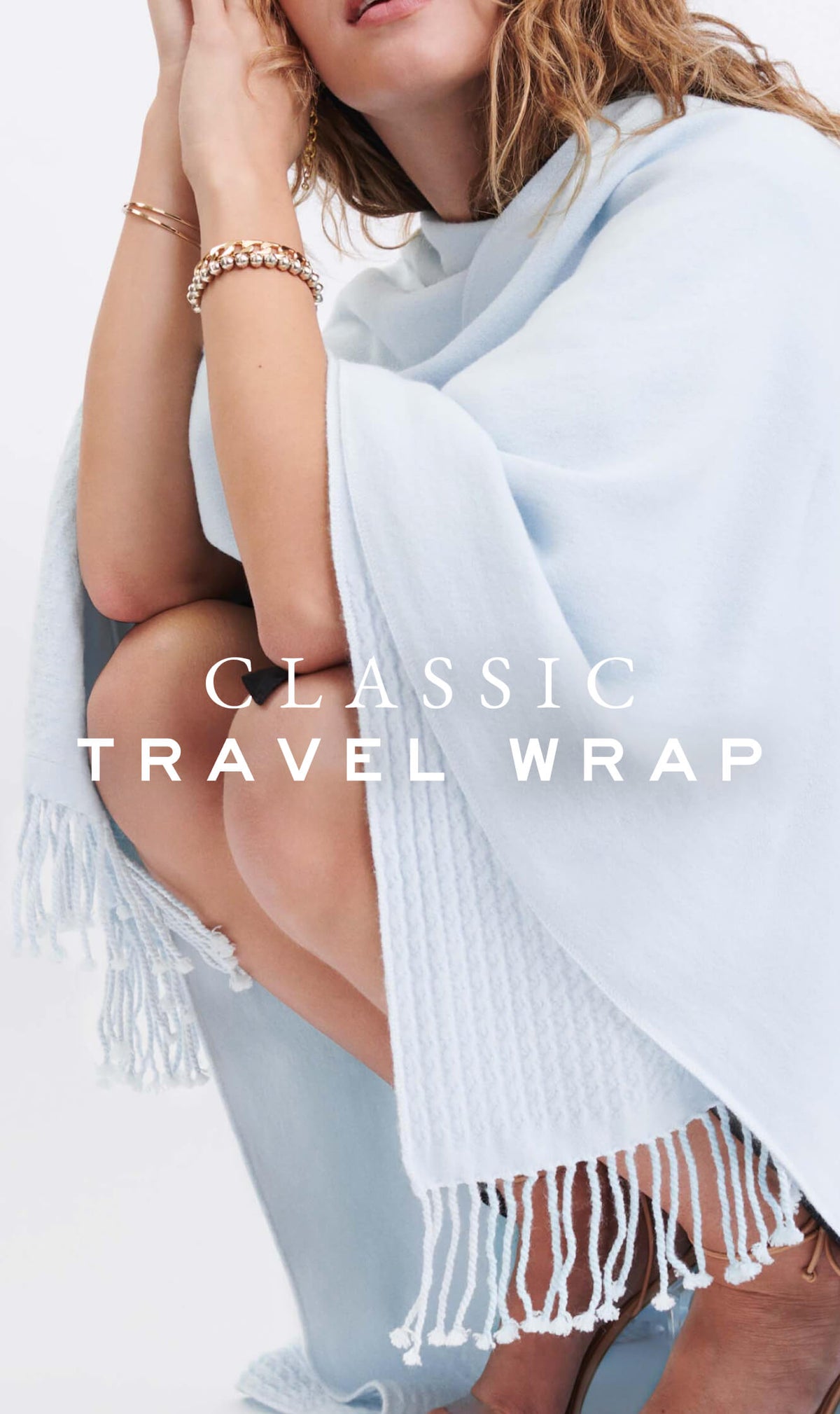 MERSEA women's travel-friendly light blue ribbed knit wrap with fringe detailing. Text: CLASSIC TRAVEL WRAP