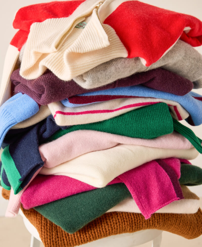 Stack of colorful sweaters on a white surface