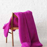 Mersea Cozy Cabin Faux Fur Throw Blanket in magenta draped over chair