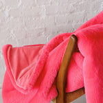 Mersea Cozy Cabin Faux Fur Throw Blanket in Pink Punch draped over a chair