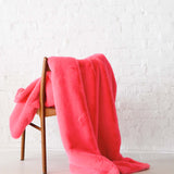 Mersea Cozy Cabin Faux Fur Throw Blanket in Pink Punch draped over a chair